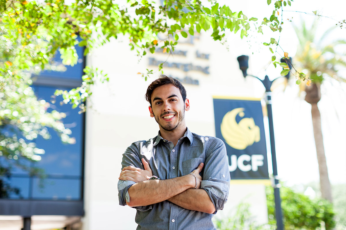 Male student standing outside infront of UCF sign