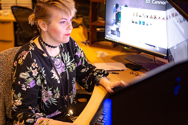 Female student working infront of 3 screen displays
