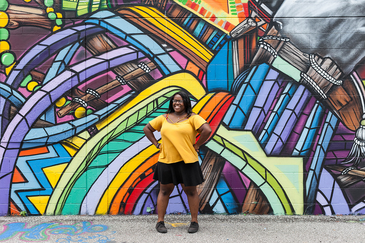 Female student posing outside infront of graffiti filled wall