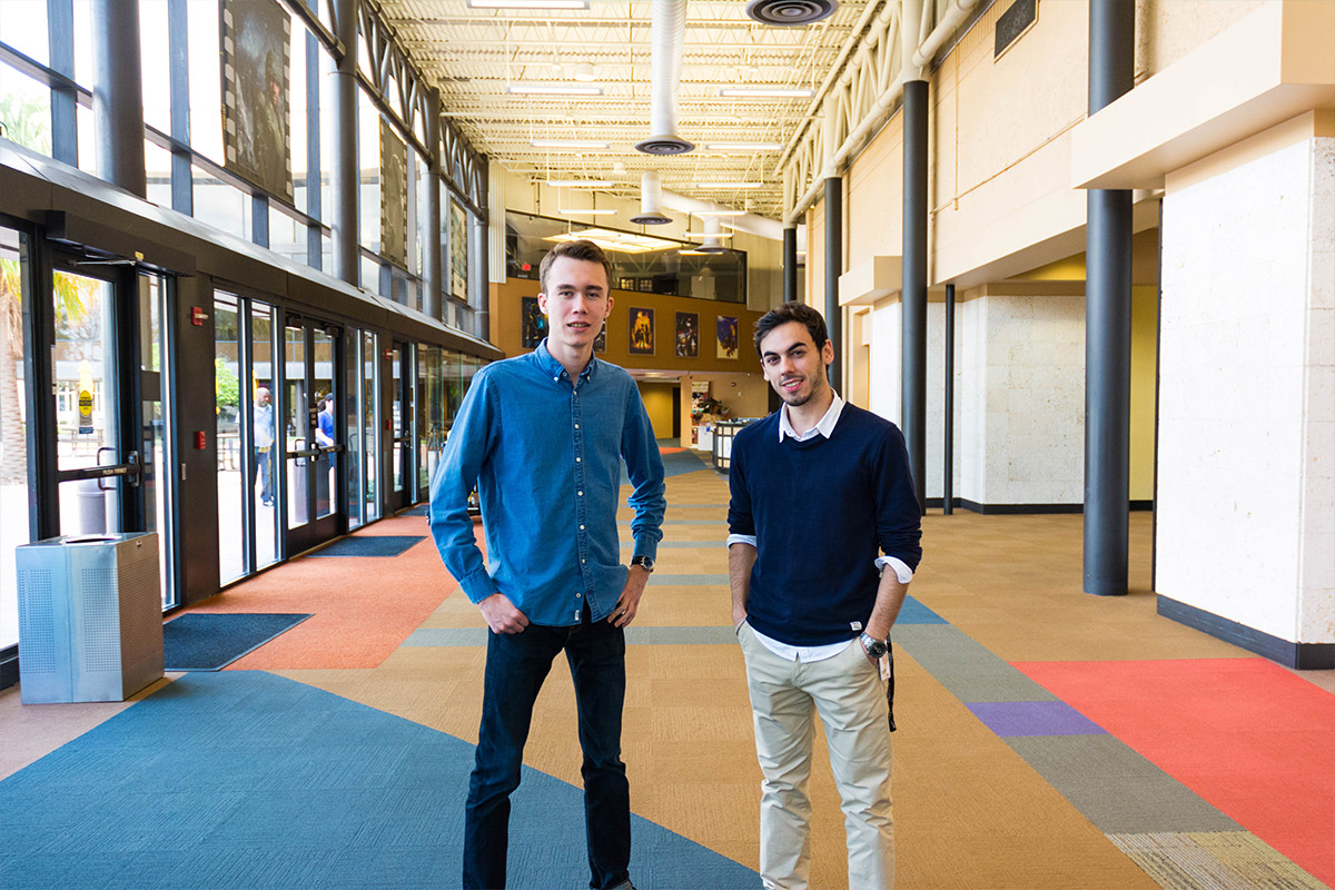 Two male students standing inside of FIEA lobby