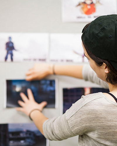 Young female student pinning pictures onto a wall