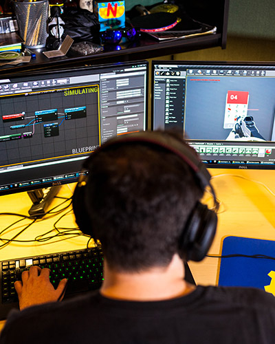 Young male student with headphones on working at his desk