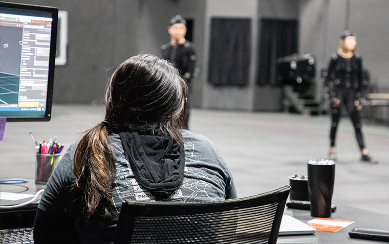 Female student overlooking two mocap actors on a mocap stage