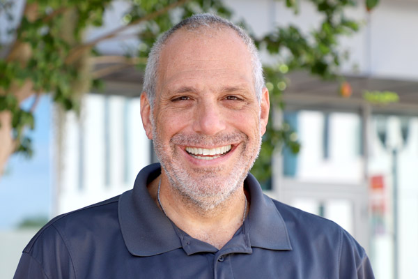 Headshot of John Rotolo with big smile outside the CMB building at UCF Downtown