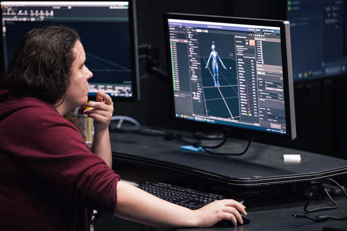 A UCF FIEA student in Professor Cheryl Briggs' MOCAP workshop works at a computer in the Shogun software program at the MOCAP stage in FIEA's Studio 500.